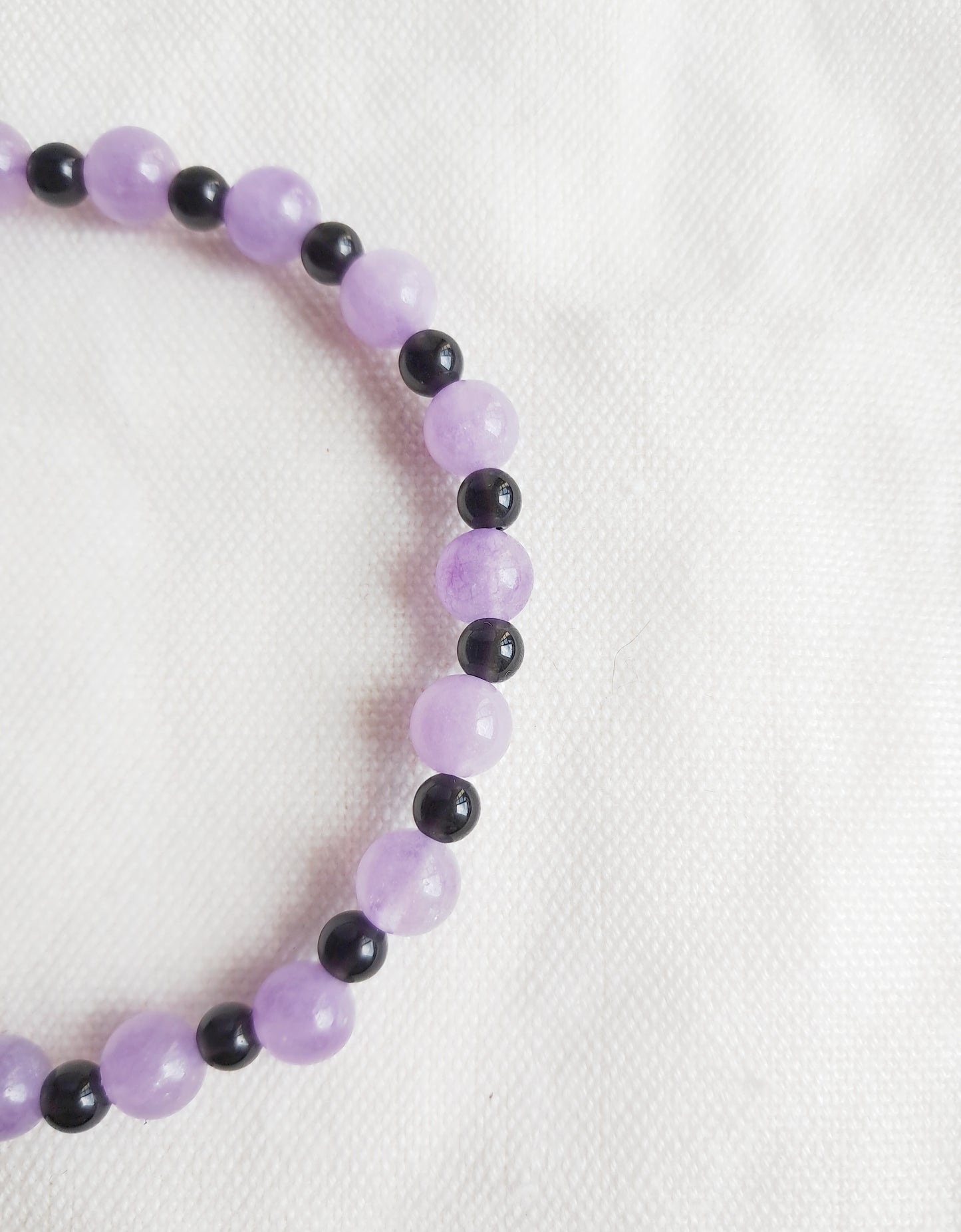 Détail des perles en calcédoine violette et obsidienne