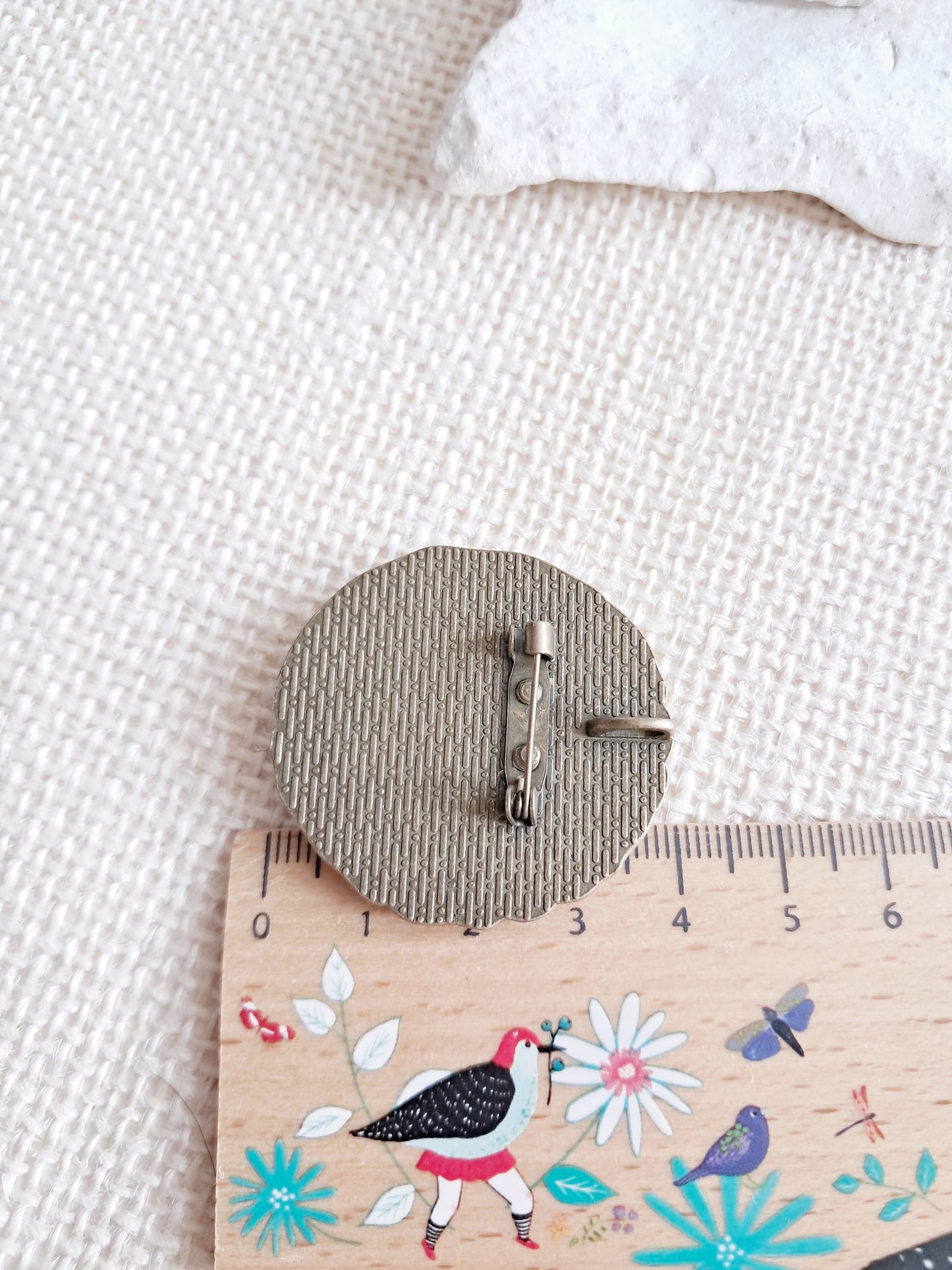 Broche cabochon oiseau posé sur une branche en fleurs